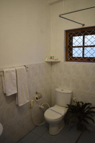 a bathroom with a toilet and a window and towels at Paradise Inn in Kandy