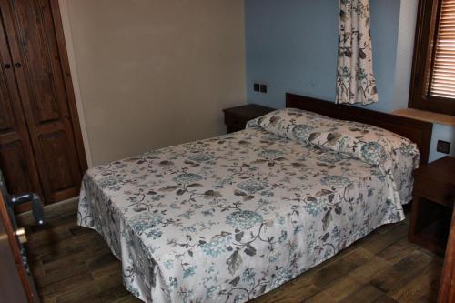 a bedroom with a bed with a floral bedspread at Hotel Maram in Tangier