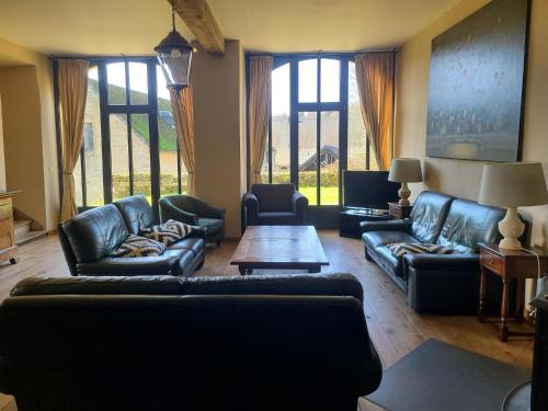 a living room with couches and a table and windows at Accommodation in the forges of Orval in Abbaye dʼOrval