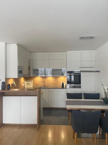a kitchen with white cabinets and a table with chairs at Lake View Apartment Seecorso in Velden am Wörthersee
