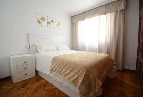een witte slaapkamer met een bed en een raam bij Piso en pleno centro de Vilagarcía de Arousa in Vilagarcia de Arousa