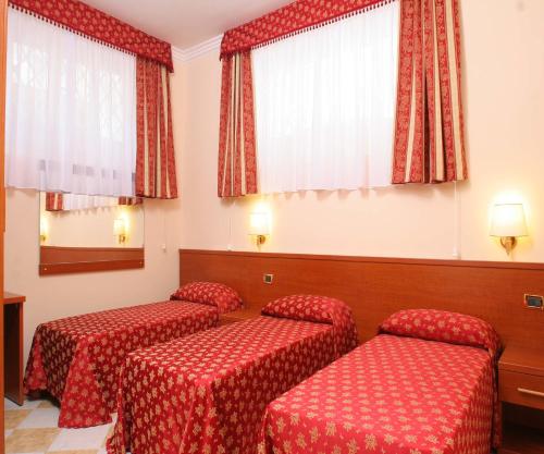 a hotel room with three red beds and curtains at Hotel Chicago in Rome