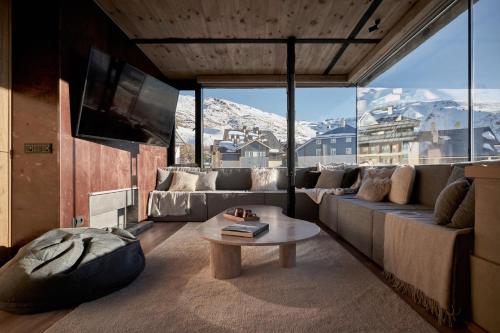 een woonkamer met een bank en een tafel bij AticoNevado - Apartamento de lujo con vistas panoramicas 360 in Sierra Nevada
