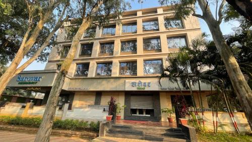 a building on the street with trees in front of it at Hotel Sarovar Residency in Boisar