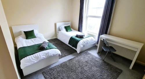 a small bedroom with two beds and a window at Ruby Retreat - Entire House - WiFi - 4 Bed - Garden - Maidstone Town in Maidstone