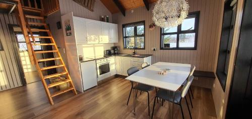 une cuisine avec une table, des chaises et une échelle dans l'établissement Smáratún Cottages & Chalets, à Hellisholar