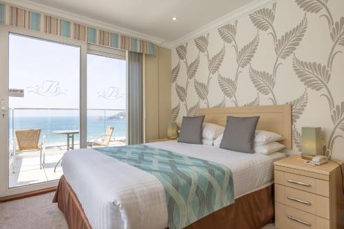 a bedroom with a bed with a view of the ocean at Biarritz Hotel in St Brelade