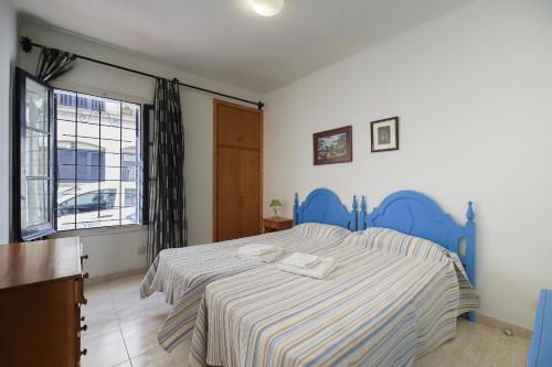 Un dormitorio con una cama con cabecero azul y una ventana. en 1Auro - Calella de Palafrugell, en Calella de Palafrugell