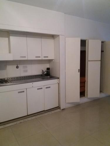 una cocina vacía con armarios blancos y una puerta abierta en Juncal Apartment en Buenos Aires