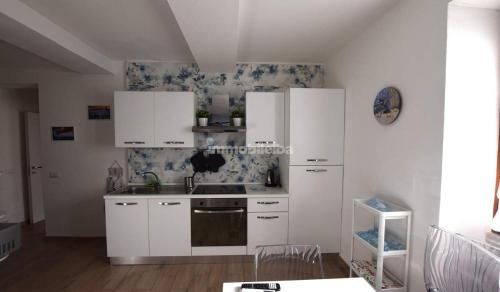 a kitchen with white cabinets and a stove top oven at Casa Tua in Marina di Campo