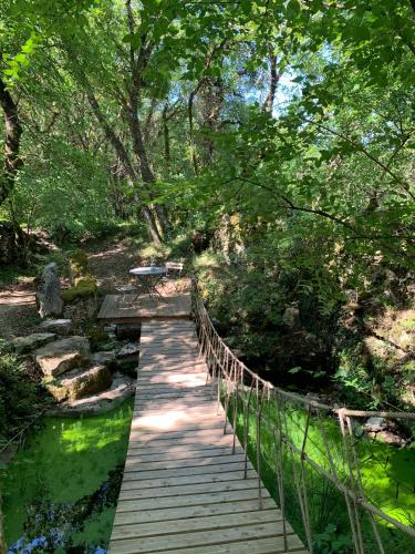 a wooden bridge over a stream in a park at cabane lodge avec spa privatif in Livernon