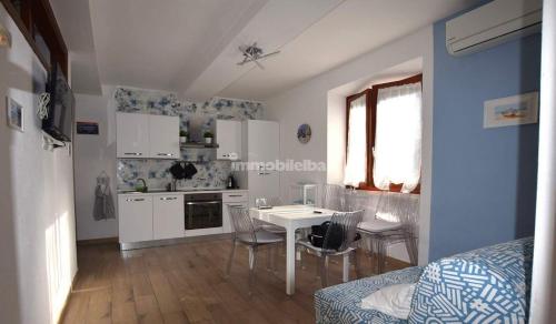 a white kitchen with a table and chairs in a room at Casa Tua in Marina di Campo