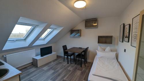 a room with a bed and a table and a tv at Europa City Apartment in Saarbrücken