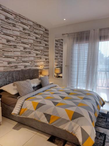 a bedroom with a large bed with a stone wall at Forest View Apartments in Kololi