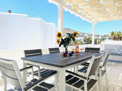 a table and chairs on a balcony with a table and flowers at Aphrodite sunshine suite in Mýkonos City