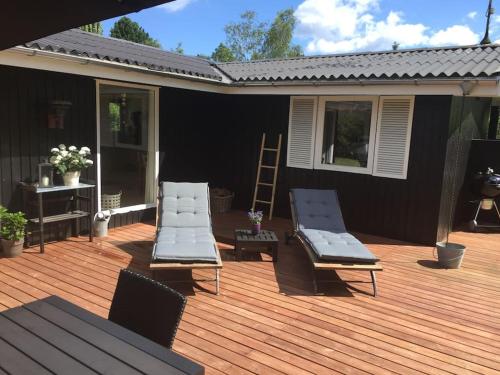 a deck with two lounge chairs on a house at En perle af et sommerhus tæt på både strand og by in Hornbæk