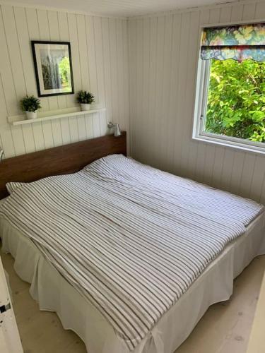 a bed sitting in a bedroom with a window at En perle af et sommerhus tæt på både strand og by in Hornbæk