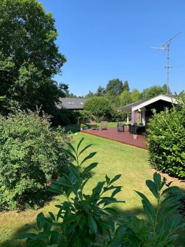 a yard with a house with a patio and trees at En perle af et sommerhus tæt på både strand og by in Hornbæk