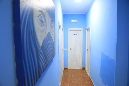 un couloir avec des murs bleus et une peinture murale dans l'établissement First Hostel Tropea, à Tropea