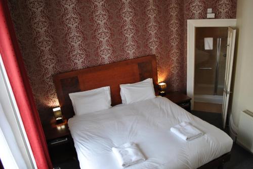 um quarto com uma cama branca com duas toalhas em Town House Rooms em Hastings