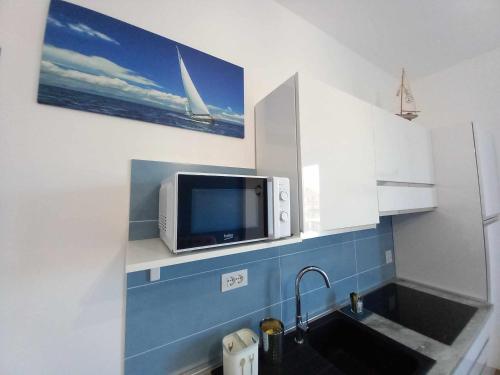 uma cozinha com um lavatório e uma televisão na parede em VELA vicino al mare BluDiPietraLigure em Pietra Ligure