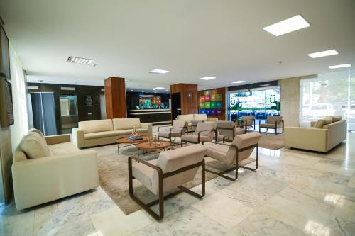 a lobby with couches and chairs in a building at Like U Hotel Brasília in Brasilia