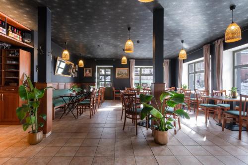 ein Restaurant mit Holztischen, Stühlen und Pflanzen in der Unterkunft Hotel Krokus in Pec pod Sněžkou