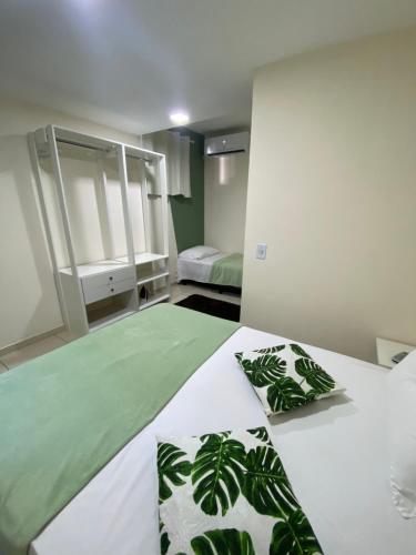 a bedroom with a bed with green and white sheets and pillows at Casa aconchegante e charmosa à 6 min da Praia - Ar condicionado - WIFI 600MB - Netflix - Globoplay - Cozinha Completa in Rio das Ostras