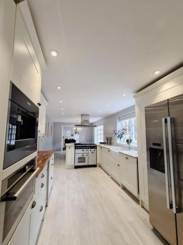 a large kitchen with white cabinets and stainless steel appliances at A luxury unique home spa - White Stones Retreats. in Weymouth