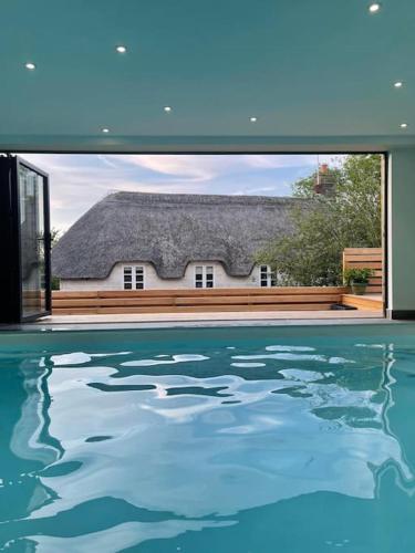 a swimming pool with a house seen through a window at A luxury unique home spa - White Stones Retreats. in Weymouth