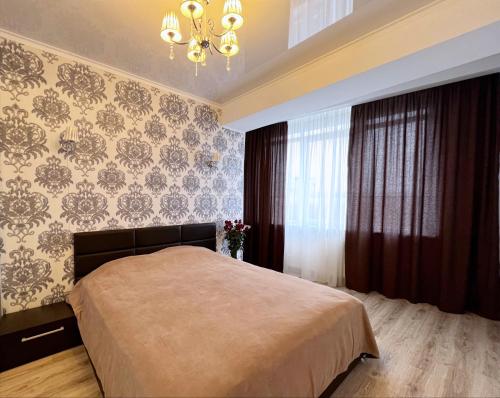 een slaapkamer met een bed en een kroonluchter bij Apartament de lux cu 2 camere și living in Chişinău