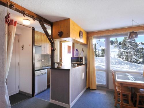 une cuisine avec un comptoir, une table et une fenêtre dans l'établissement Appartement cosy avec accès pistes, casier à skis et parking souterrain - FR-1-181-2036, à La Plagne Tarentaise