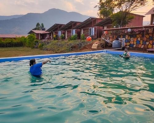 Dos personas están nadando en una piscina en Mysticstays Resort, en Wai