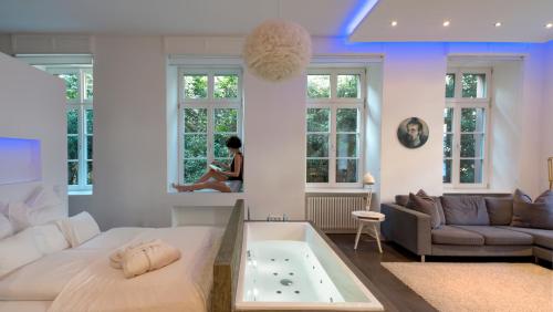 a woman sitting in a living room with a tub at Boutique Suites Heidelberg Alte Zigarrenmanufaktur in Heidelberg