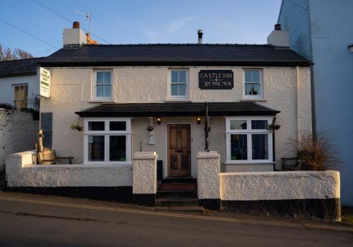a white building with a sign on the front of it at The Rum Shack Manorbier Castle Inn in Manorbier