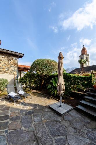 a patio with a umbrella and two chairs and a lighthouse at Rustico al Sole - Just renewed 1bedroom home in Ronco sopra Ascona in Ronco s/Ascona - Porto Ronco