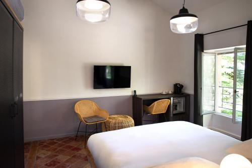 a bedroom with a bed and two chairs and a tv at Manoir le Roure in Châteauneuf-du-Rhône