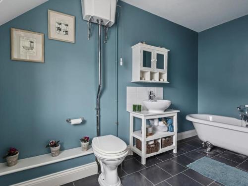 Baño azul con aseo y lavamanos en Large coastal cottage, private indoor pool, hut tub, sauna and steam pod, en Weymouth