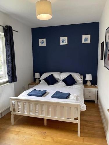 a bedroom with a white bed with blue walls at Large coastal cottage,with private indoor pool, hut tub on the Jurassic coast in Weymouth