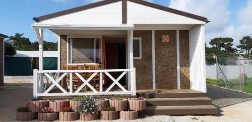 a small house with a porch and a fence at Parque de Campismo da Praia da Barra in Gafanha da Nazaré