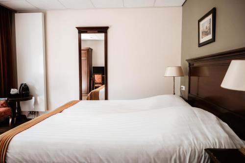 a large white bed in a hotel room at De Lunterse Boer in Lunteren