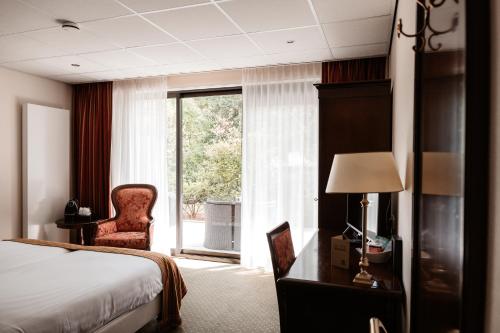 una camera d'albergo con un letto, una sedia e una finestra di De Lunterse Boer a Lunteren