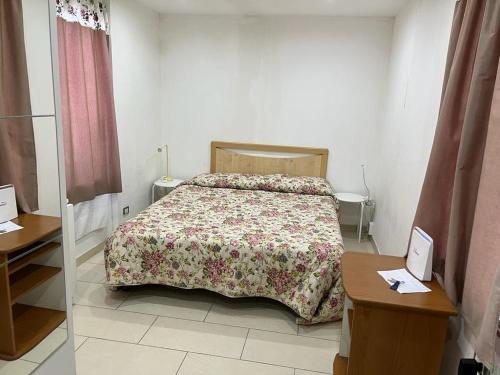 a bedroom with a bed with a floral bedspread on it at Casa Vacanze Deni in Fontane Bianche