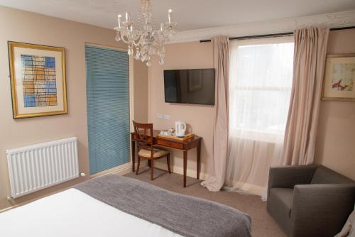 a bedroom with a bed and a desk and a chair at Royal Hotel, Bar & Grill in Purfleet
