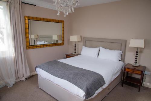 a bedroom with a large white bed and a mirror at Royal Hotel, Bar & Grill in Purfleet