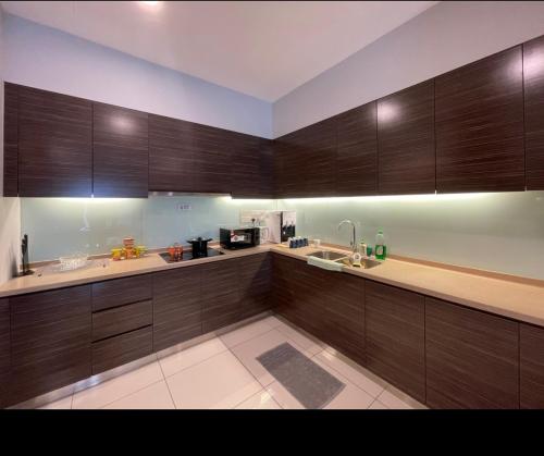 a large kitchen with wooden cabinets and a sink at Lux 3BR max 16pax Suite Puteri Habour sea view near Legoland in Nusajaya
