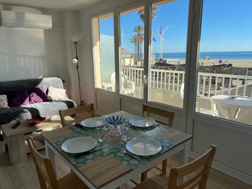 - un salon avec une table et une vue sur la plage dans l'établissement Le CARROUSEL - Apt VUE MER - Plage à 10 M - CLIM - WIFI, à Canet