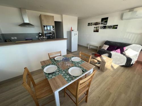 cocina y sala de estar con mesa y sillas. en Le CARROUSEL - Apt VUE MER - Plage à 10 M - CLIM - WIFI, en Canet-en-Roussillon