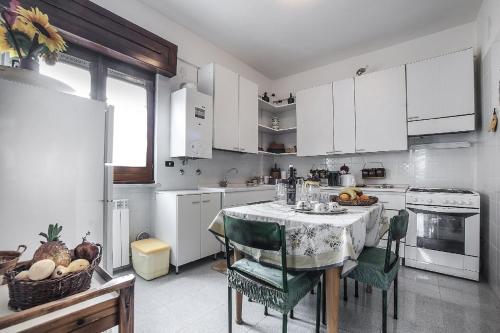 una cocina con mesa con sillas y una cocina con armarios blancos. en Passiflora House - Basilicata en Sant’Angelo