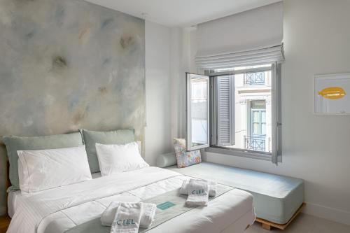 una camera da letto con un grande letto bianco e una finestra di Ciel Suites Athens ad Atene